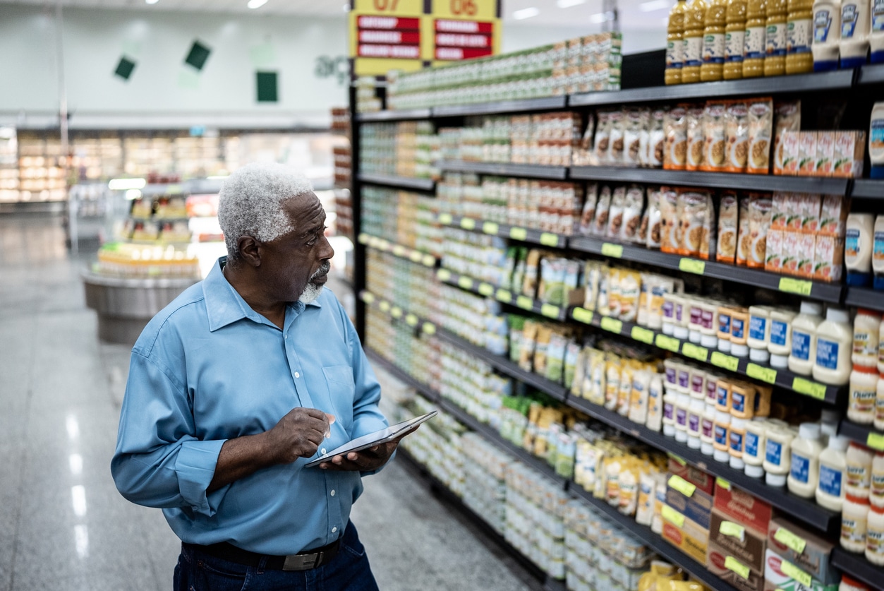 Senior man working on the digital tablet in the supermarket