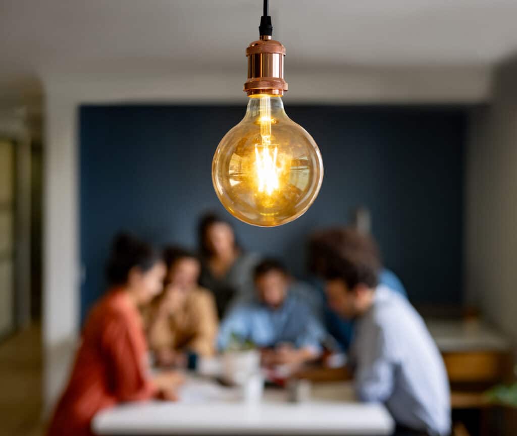 Creative team discussing a business idea in a meeting - focus on light bulb hanging above