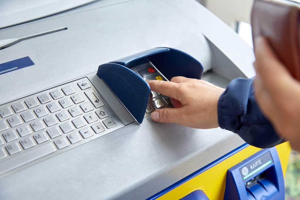 A female hand dials a personal code on the ATM keyboard