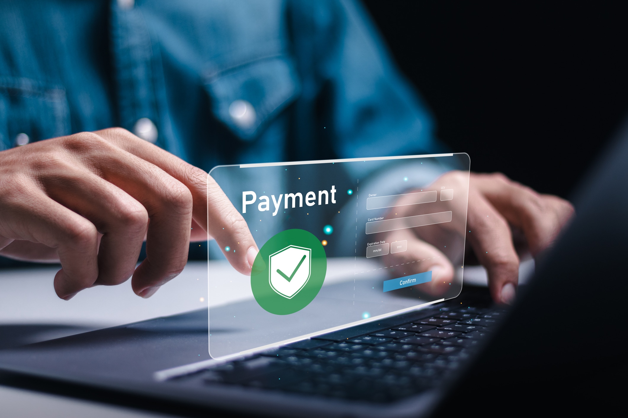 Payment graphic hovering above laptop with hand clicking it