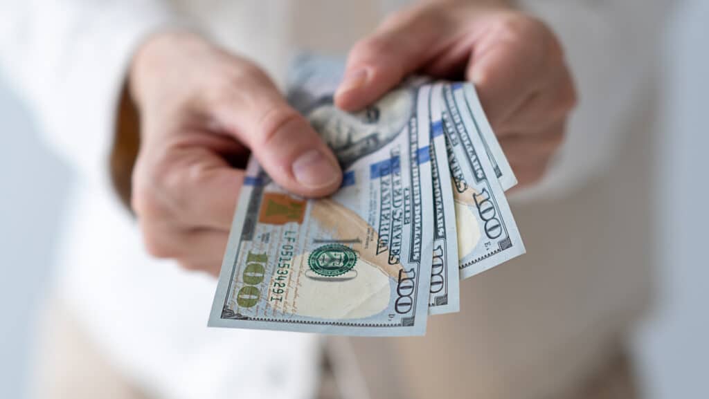 Hand holding a few $100 bills