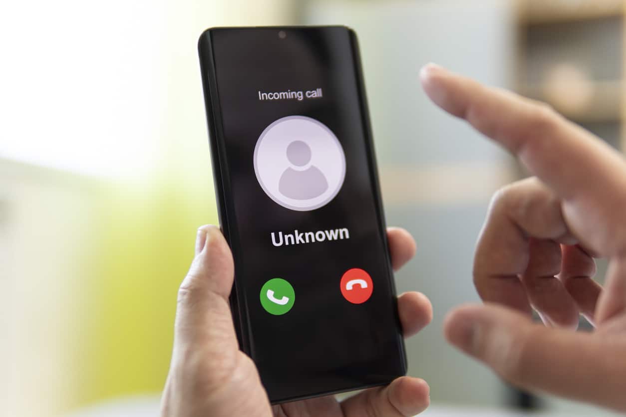Hand holding iPhone with unknown call coming in